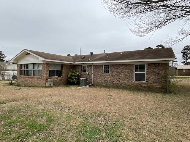 rear view of house with a yard, fence, cooling unit, and brick siding