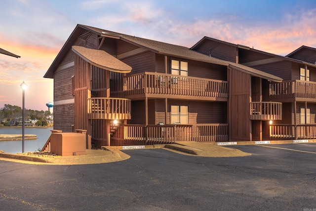 view of front of property featuring a water view, uncovered parking, and roof with shingles