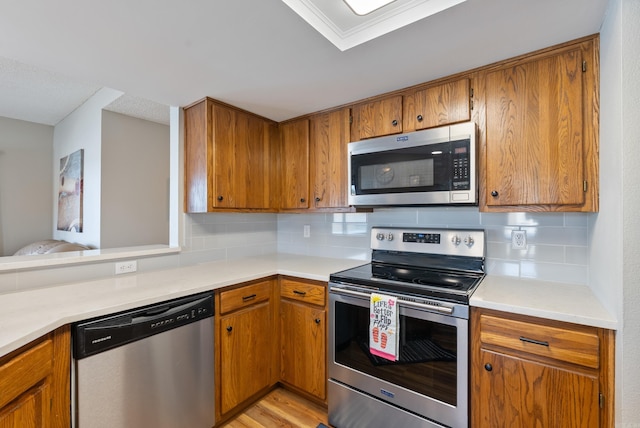 kitchen featuring stainless steel appliances, light countertops, brown cabinets, and tasteful backsplash