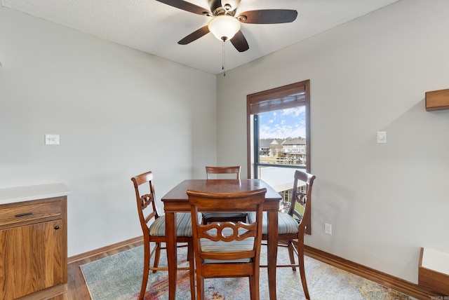 dining space featuring light wood-type flooring, a ceiling fan, and baseboards