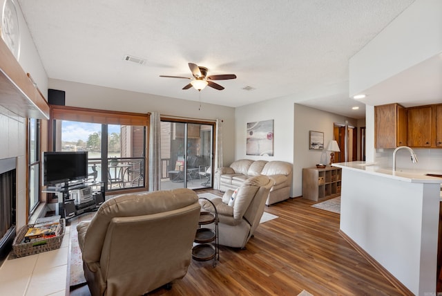 living area featuring a textured ceiling, wood finished floors, visible vents, and a ceiling fan