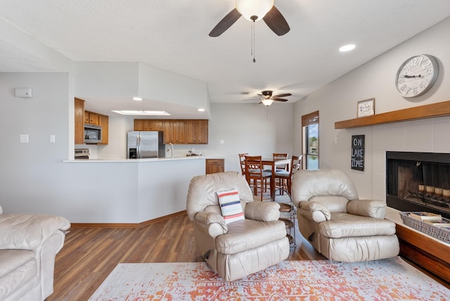 living area featuring recessed lighting, a ceiling fan, a textured ceiling, wood finished floors, and a tile fireplace