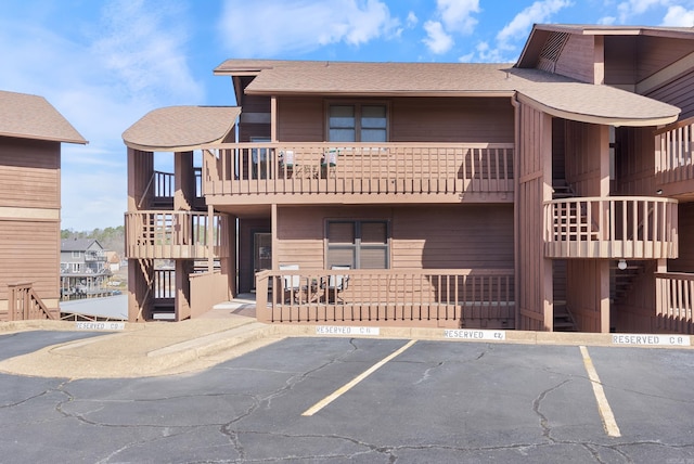 view of property featuring uncovered parking and stairway