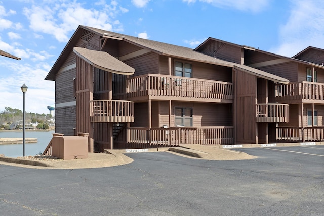 view of building exterior with uncovered parking and a water view