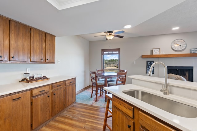 kitchen featuring light countertops, light wood finished floors, a sink, and brown cabinets