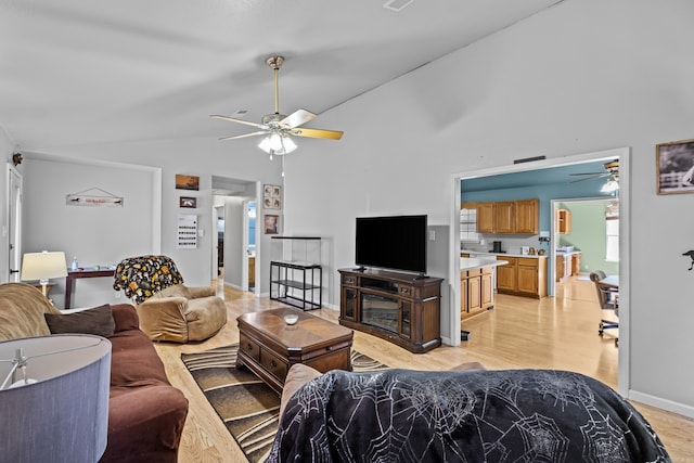 living area with a ceiling fan, light wood-type flooring, high vaulted ceiling, and baseboards