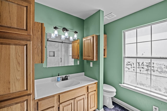 bathroom featuring toilet, vanity, visible vents, baseboards, and a shower