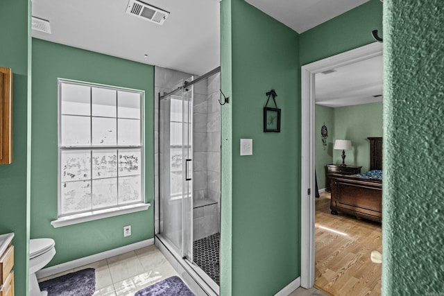 ensuite bathroom featuring visible vents, toilet, a stall shower, connected bathroom, and baseboards