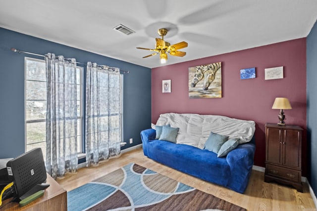 living area featuring visible vents, ceiling fan, baseboards, and wood finished floors