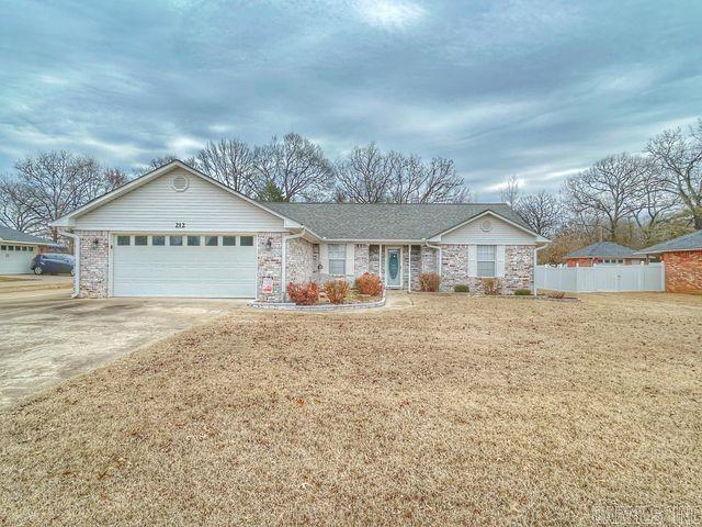 ranch-style home featuring an attached garage, fence, a front lawn, and concrete driveway