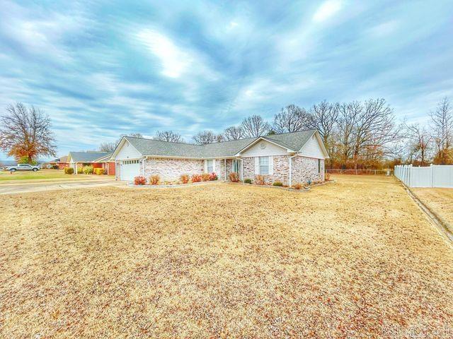 ranch-style home featuring a front lawn, fence, and an attached garage