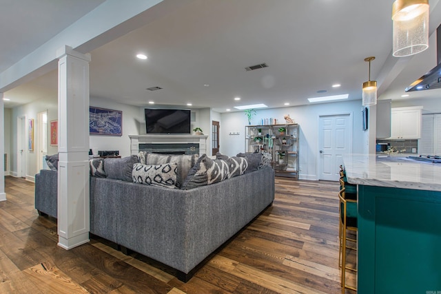 living area with visible vents, dark wood-style flooring, decorative columns, and recessed lighting