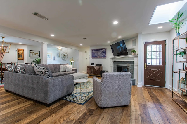 living area with a brick fireplace, visible vents, dark wood-type flooring, and recessed lighting