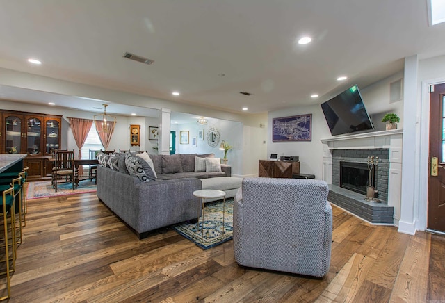 living room with a fireplace, visible vents, dark wood-type flooring, and recessed lighting