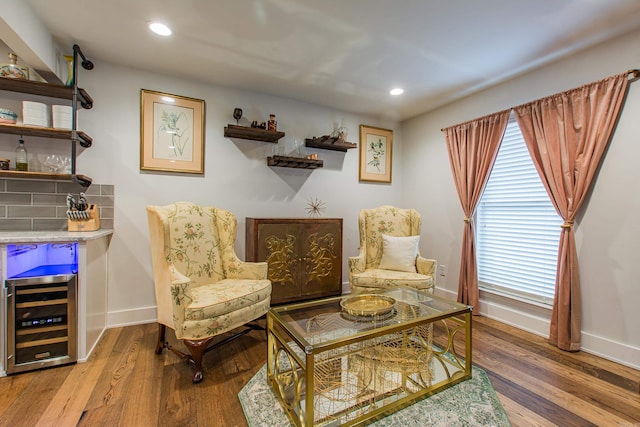 living area with a dry bar, wine cooler, baseboards, and wood finished floors