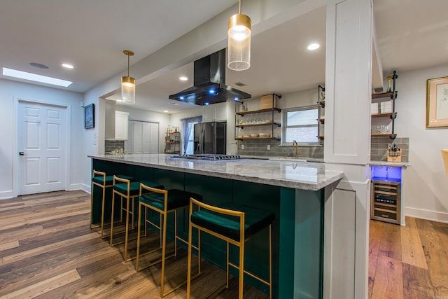 kitchen featuring island range hood, beverage cooler, dark wood-style flooring, refrigerator with ice dispenser, and white cabinets