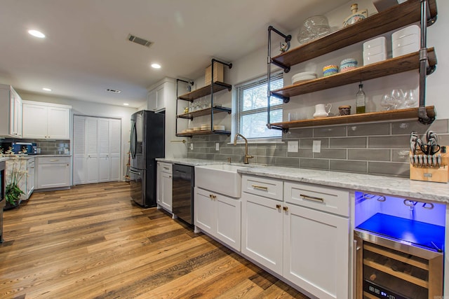 kitchen with beverage cooler, light wood-type flooring, black appliances, open shelves, and a sink