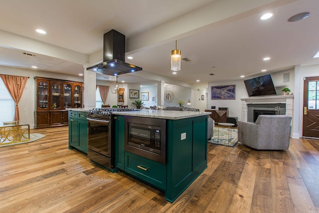 kitchen featuring light wood-style flooring, island range hood, visible vents, appliances with stainless steel finishes, and green cabinetry