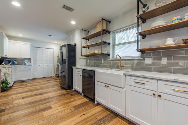 kitchen featuring dishwashing machine, a sink, visible vents, freestanding refrigerator, and open shelves