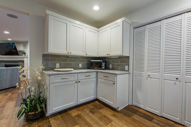 kitchen featuring light stone countertops, dark wood-style floors, a toaster, and decorative backsplash