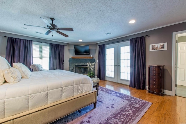 bedroom with a textured ceiling, wood finished floors, visible vents, french doors, and crown molding