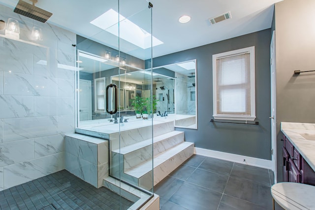 bathroom with a skylight, baseboards, visible vents, a shower with shower door, and vanity