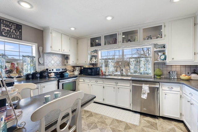 kitchen featuring stainless steel appliances, dark countertops, a sink, and open shelves