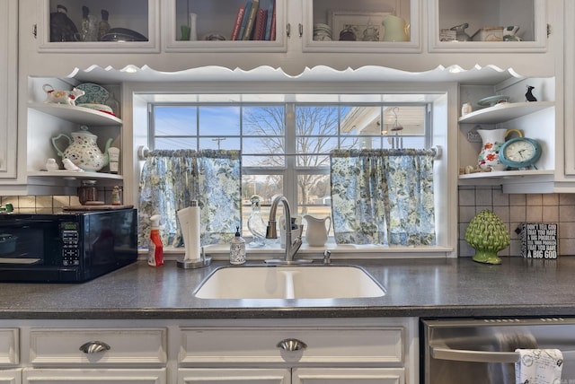 kitchen with open shelves, dark countertops, stainless steel dishwasher, a sink, and black microwave