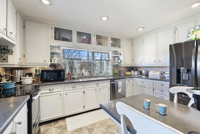 kitchen with open shelves, appliances with stainless steel finishes, dark countertops, and a sink