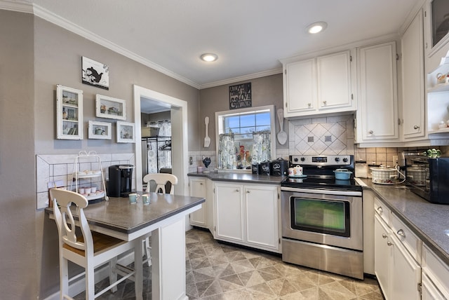 kitchen with dark countertops, electric range, decorative backsplash, ornamental molding, and white cabinets