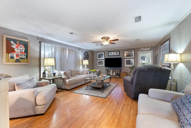 living room with a ceiling fan, visible vents, ornamental molding, and wood finished floors