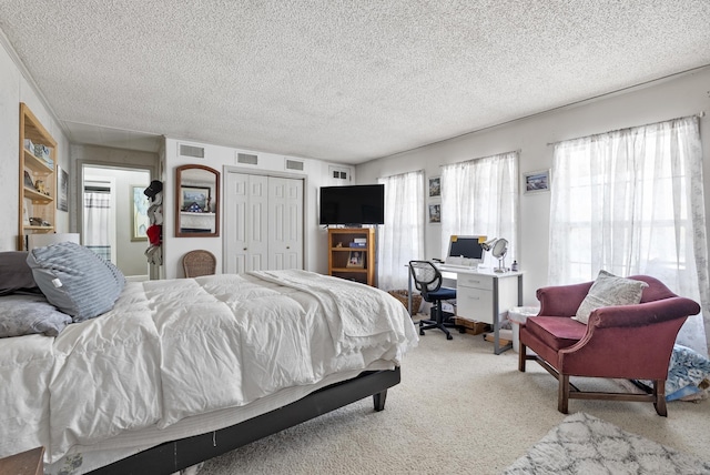 bedroom featuring light carpet, a closet, a textured ceiling, and visible vents