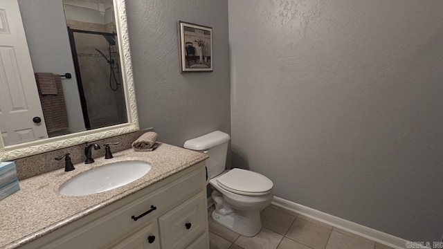 bathroom featuring toilet, a stall shower, vanity, baseboards, and tile patterned floors