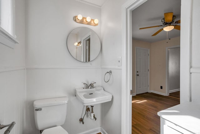 half bath with a sink, wood finished floors, toilet, and a ceiling fan