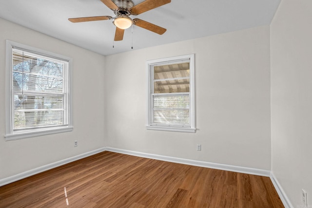 spare room featuring a ceiling fan, plenty of natural light, baseboards, and wood finished floors