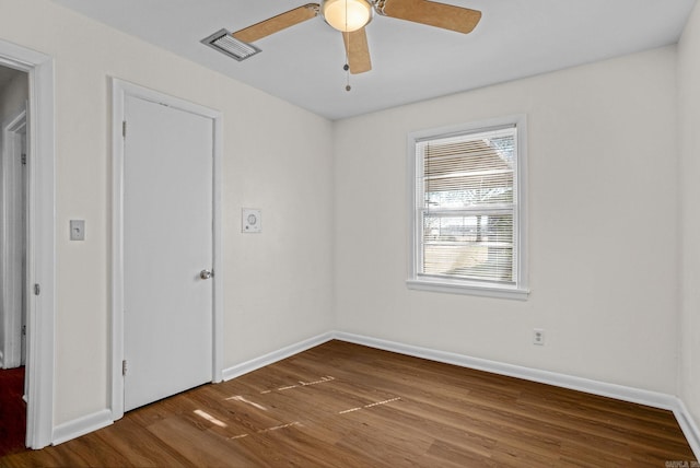 spare room featuring wood finished floors, visible vents, and baseboards