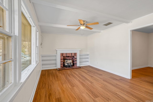 unfurnished living room with visible vents, beamed ceiling, baseboards, and wood finished floors