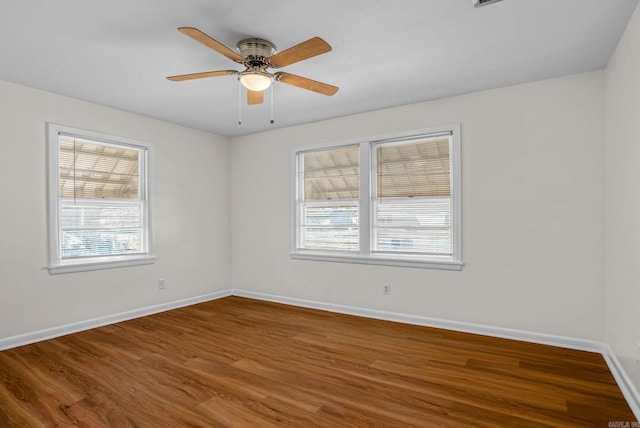 empty room featuring ceiling fan, baseboards, and wood finished floors