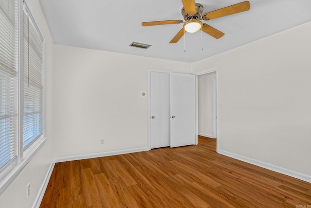 unfurnished bedroom with a ceiling fan, baseboards, visible vents, and wood finished floors