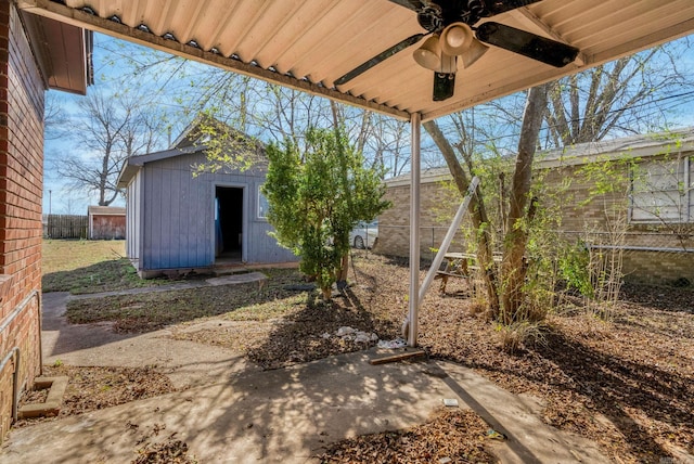 view of patio with a ceiling fan, an outbuilding, and fence