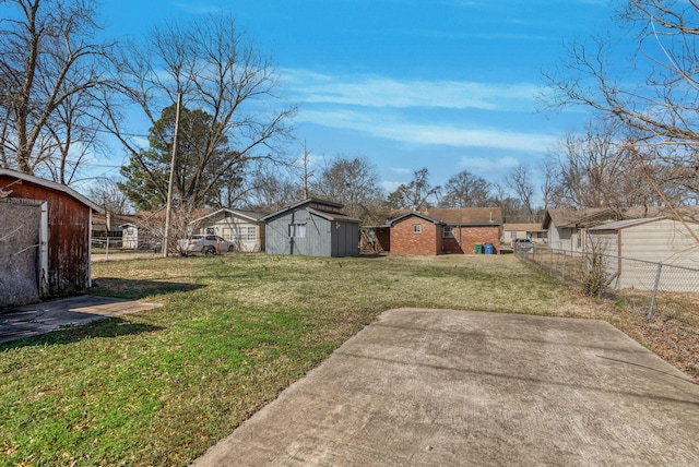 view of yard featuring an outbuilding, fence, and a shed