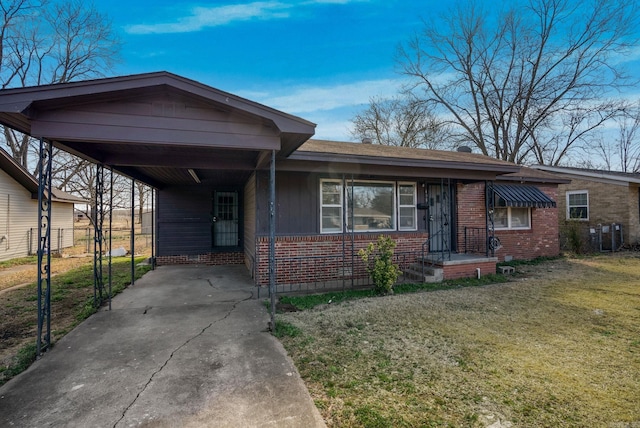 view of front of house with a carport, concrete driveway, brick siding, and a front lawn