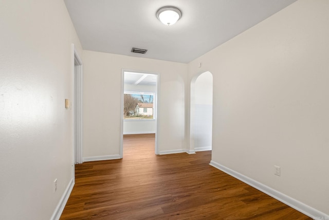 interior space with arched walkways, visible vents, baseboards, and wood finished floors