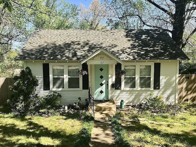 view of front of house with a shingled roof and fence