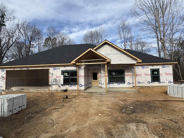 unfinished property featuring roof with shingles and an attached garage