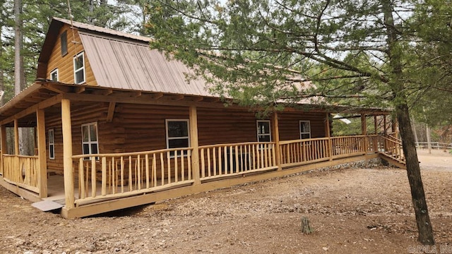 view of side of property with metal roof, a porch, and a gambrel roof