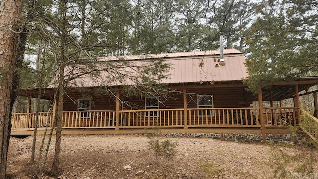 rear view of property featuring covered porch and metal roof