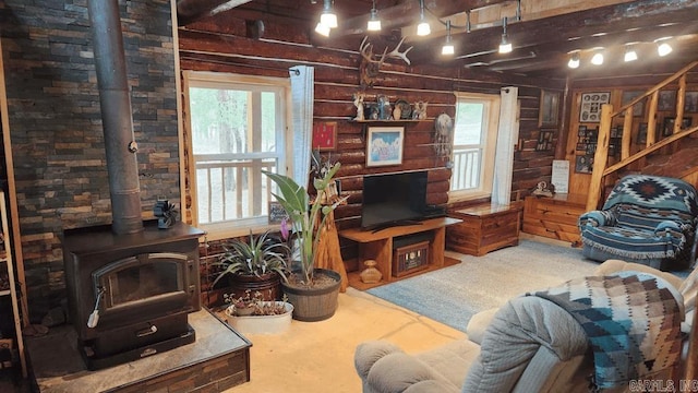 carpeted living area with a wealth of natural light, rustic walls, and a wood stove