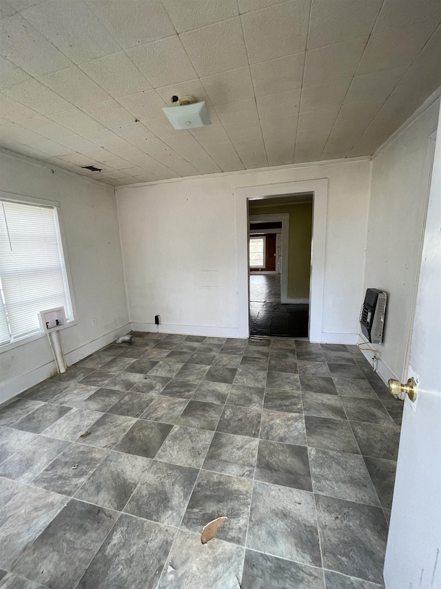 empty room featuring heating unit, stone finish floor, and baseboards