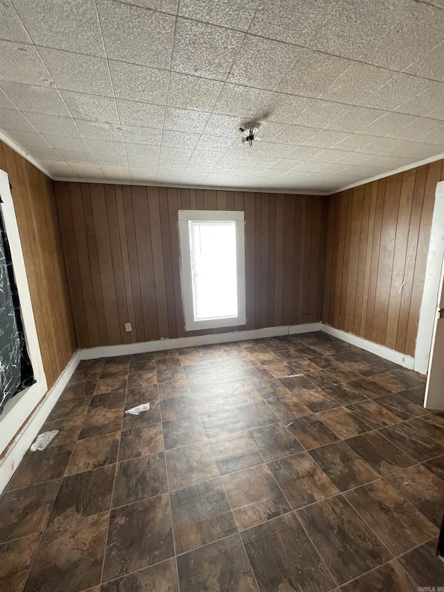 empty room with baseboards and wood walls